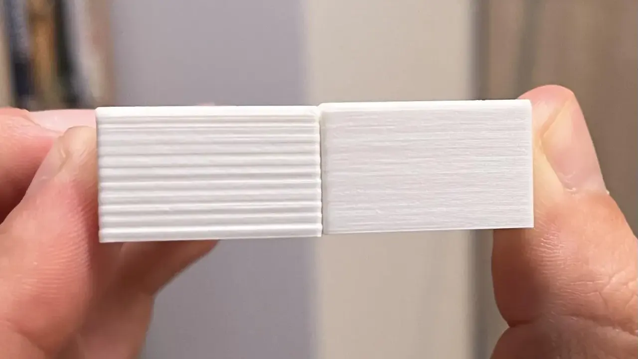Due campioni stampati in 3D, uno con evidenti linee orizzontali dovute a z wobble, l'altro liscio.