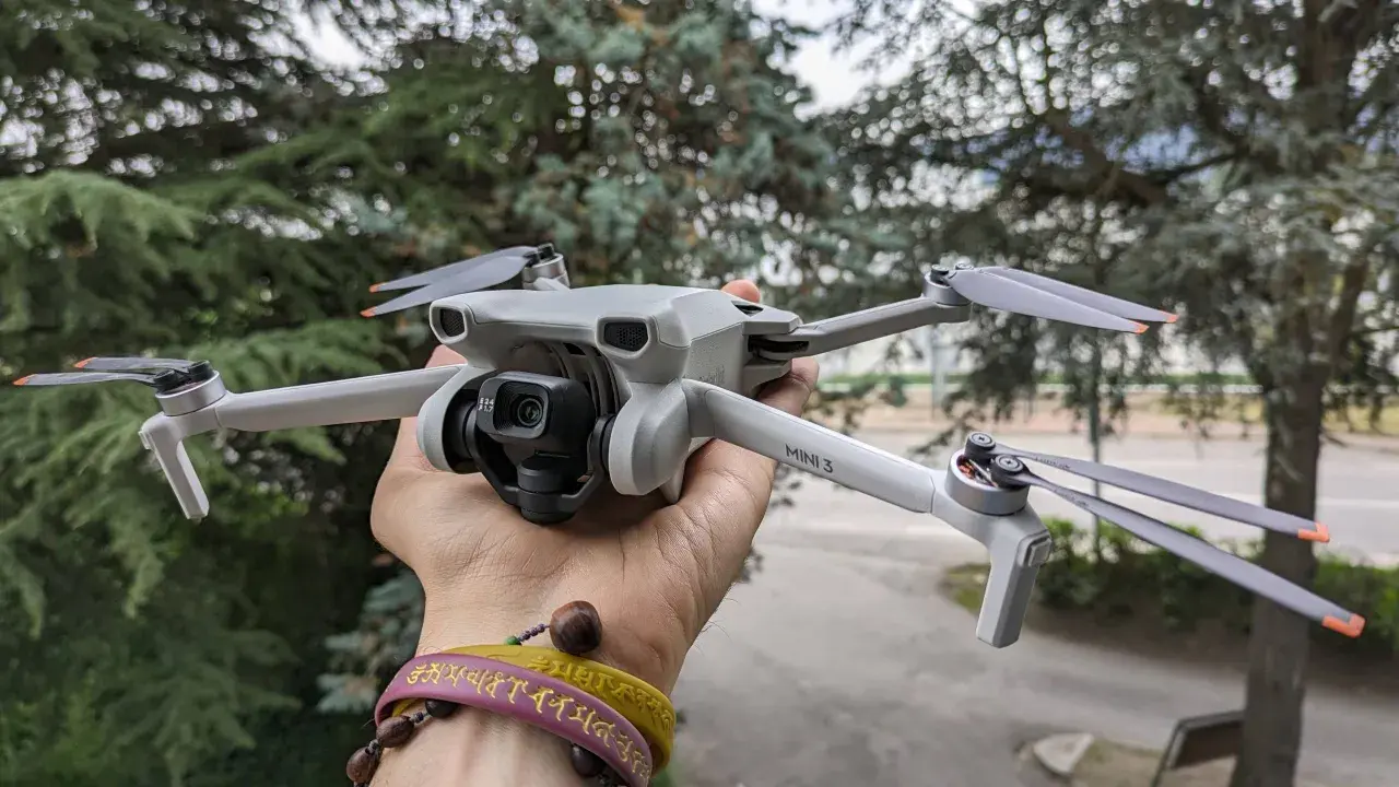 Un drone DJI Mini 3 Pro, perfetto per chi cerca un drone DJI senza patentino, tenuto in mano con alberi sullo sfondo.