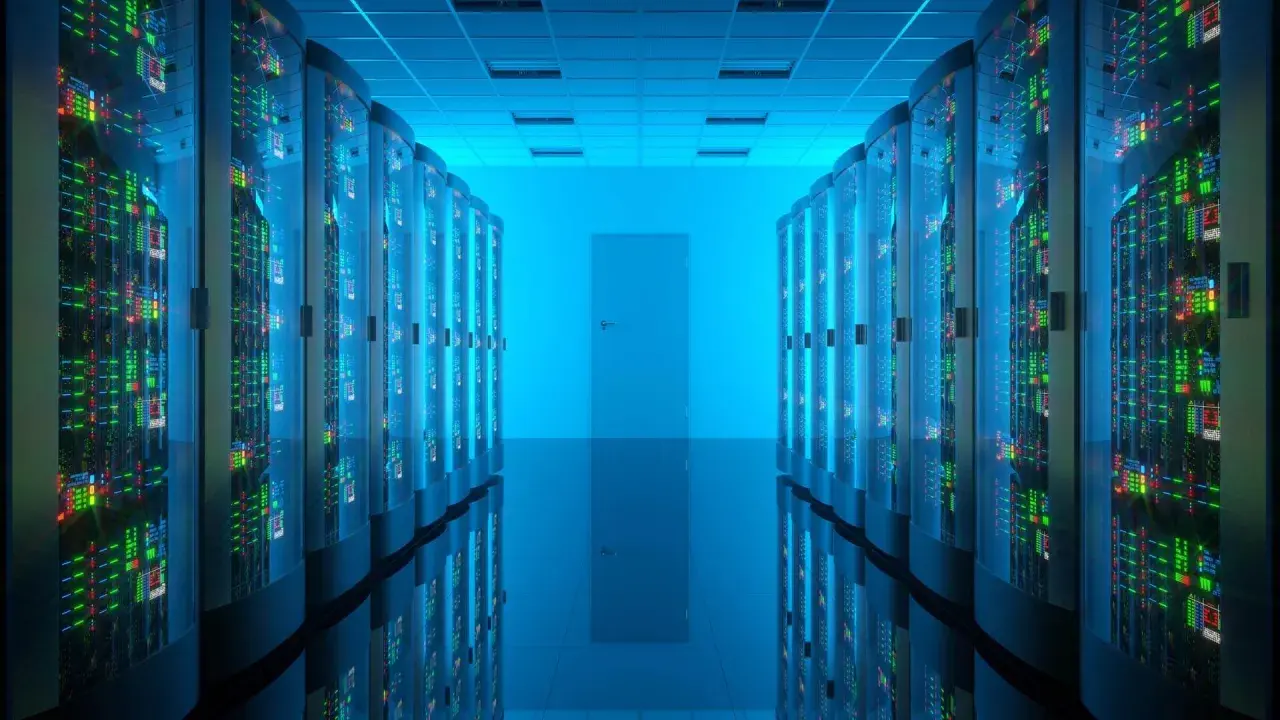 Corridoio di un data center con file di server luminosi. Qui risiede la risposta a cos'è un database: un sistema organizzato per archiviare e gestire dati.