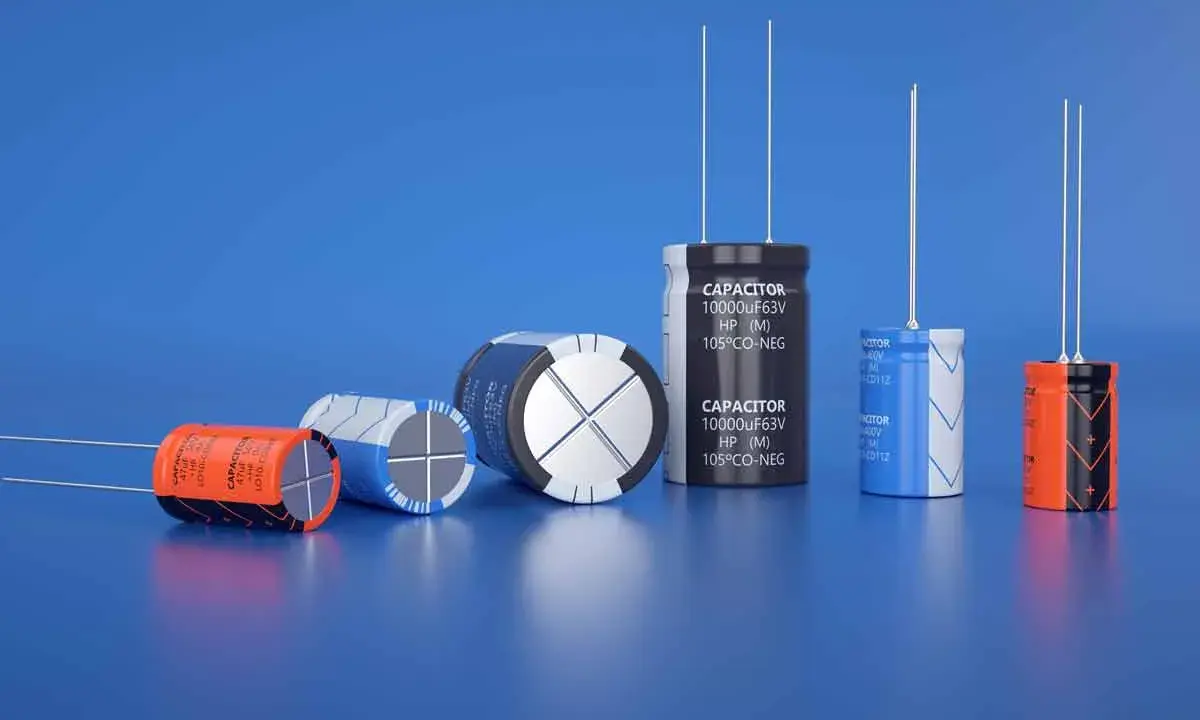 Varietà di condensatori di diverse dimensioni e colori, alcuni con etichette visibili, disposti su sfondo blu.