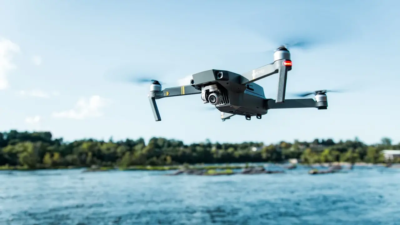 Drone in volo sopra un fiume, pronto per nuove avventure nel rispetto del regolamento droni 2024.