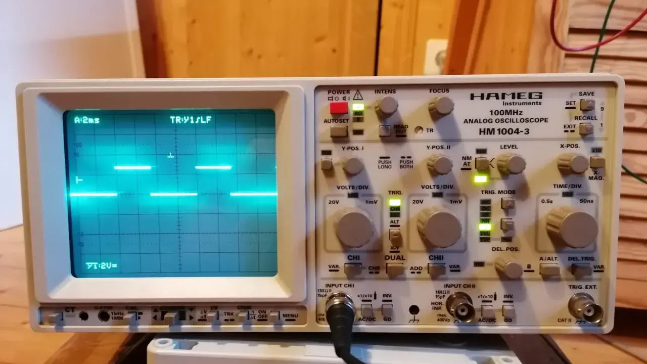 Un oscilloscopio Hamg HM 1004-3 mostra un segnale a onda quadra, probabilmente generato da un Arduino, con impostazioni di tempo e voltaggio visibili.