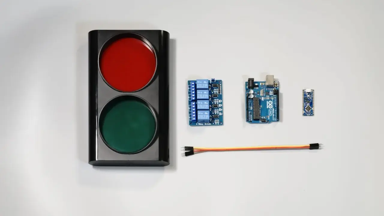 Componenti per un semaforo fai da te: un corpo con luci rosse e verdi, schede Arduino, un modulo relè e cavi.