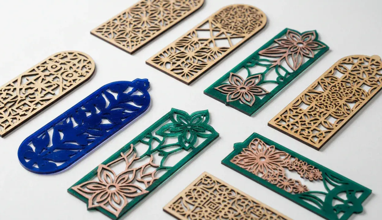 Segnalibri in legno e acrilico con intricati **progetti laser** floreali e geometrici.