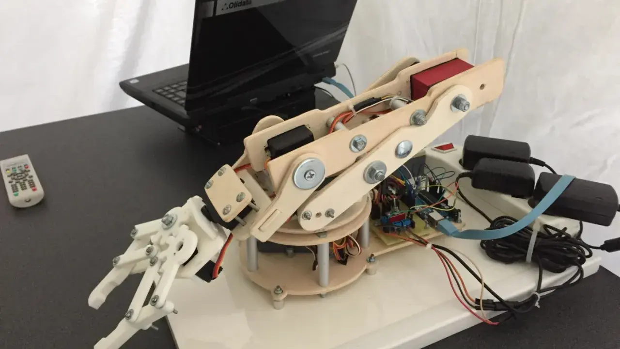 Mano robotica Arduino in legno e plastica, collegata a un laptop e alimentata da adattatori.