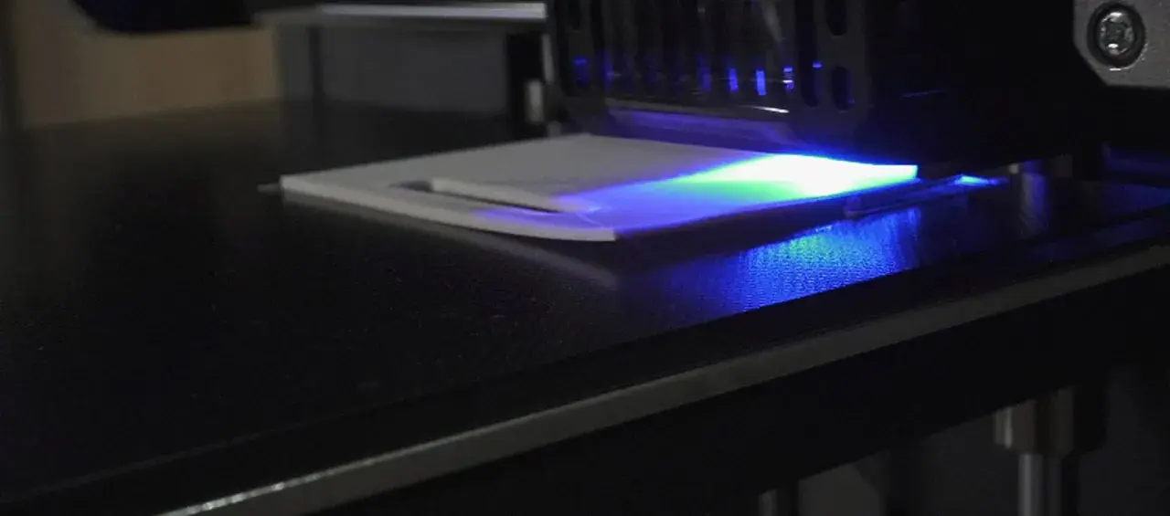 La stampa 3D in resina mostra un leggero warping, con la luce UV che illumina la superficie.