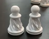 Due pedine degli scacchi bianche, stampate in 3D con filamento pla acetone, con un design a spirale.