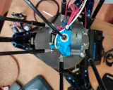 Parti di una Anycubic Kossel Linear Plus, con cavi rossi e bianchi che si snodano attorno all'estrusore blu.