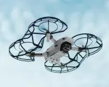 Un drone bianco con protezioni nere vola nel cielo azzurro. Perfetto per la tua scuola di droni.
