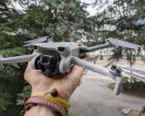 Un drone DJI Mini 3 Pro, perfetto per chi cerca un drone DJI senza patentino, tenuto in mano con alberi sullo sfondo.