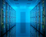 Corridoio di un data center con file di server luminosi. Qui risiede la risposta a cos'è un database: un sistema organizzato per archiviare e gestire dati.