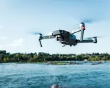 Drone in volo sopra un fiume, pronto per nuove avventure nel rispetto del regolamento droni 2024.