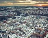 Vista aerea di un paesaggio urbano innevato al tramonto, con un drone che sorvola il Lussemburgo.