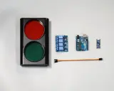 Componenti per un semaforo fai da te: un corpo con luci rosse e verdi, schede Arduino, un modulo relè e cavi.