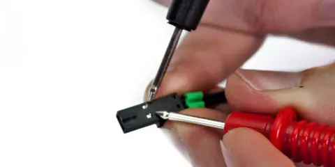 Mani che testano un connettore con puntali, forse per verificare un termistore in corto.