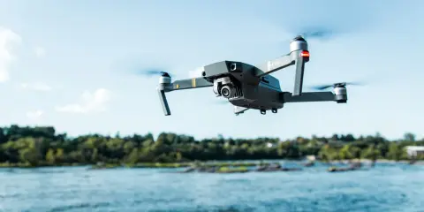 Drone in volo sopra un fiume, pronto per nuove avventure nel rispetto del regolamento droni 2024.