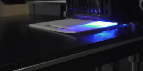La stampa 3D in resina mostra un leggero warping, con la luce UV che illumina la superficie.