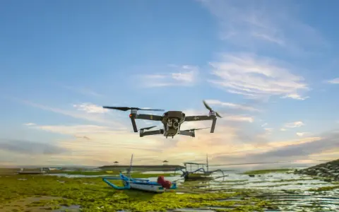 Un drone sorvola una spiaggia croata al tramonto, con barche tradizionali e alghe verdi sulla riva.