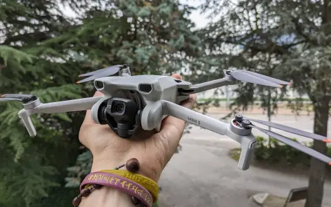 Un drone DJI Mini 3 Pro, perfetto per chi cerca un drone DJI senza patentino, tenuto in mano con alberi sullo sfondo.