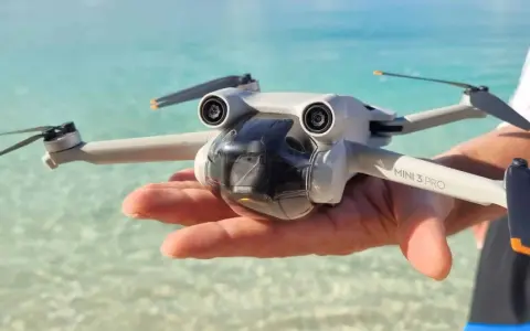 Un drone Mini 3 Pro tenuto in mano su una spiaggia tropicale, pronto per foto droni mozzafiato.