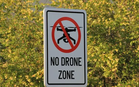 Cartello "No Drone Zone" in Italia, con un drone barrato. La natura circostante è rigogliosa e verde.