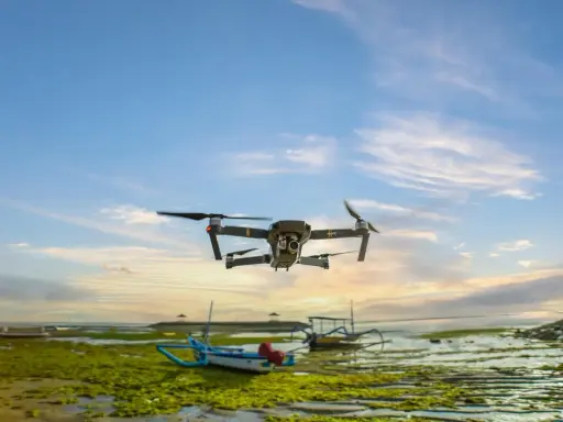 Un drone sorvola una spiaggia croata al tramonto, con barche tradizionali e alghe verdi sulla riva.