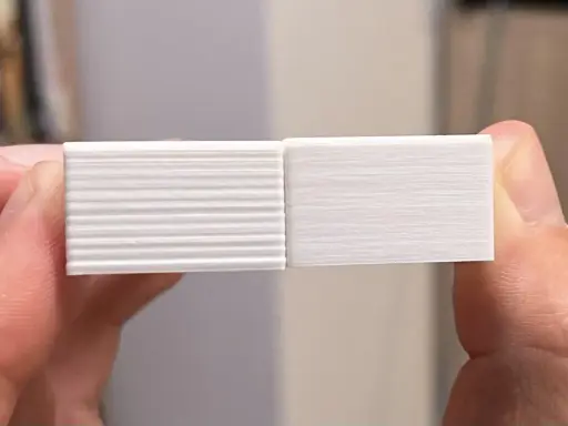 Due campioni stampati in 3D, uno con evidenti linee orizzontali dovute a z wobble, l'altro liscio.