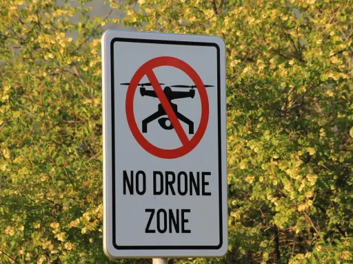 Cartello "No Drone Zone" in Italia, con un drone barrato. La natura circostante è rigogliosa e verde.