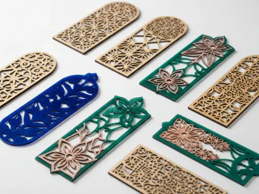 Segnalibri in legno e acrilico con intricati **progetti laser** floreali e geometrici.