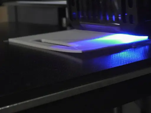La stampa 3D in resina mostra un leggero warping, con la luce UV che illumina la superficie.