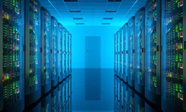 Corridoio di un data center con file di server luminosi. Qui risiede la risposta a cos'è un database: un sistema organizzato per archiviare e gestire dati.