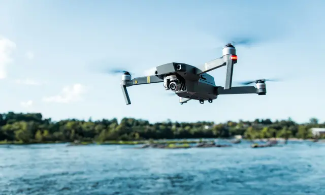 Drone in volo sopra un fiume, pronto per nuove avventure nel rispetto del regolamento droni 2024.
