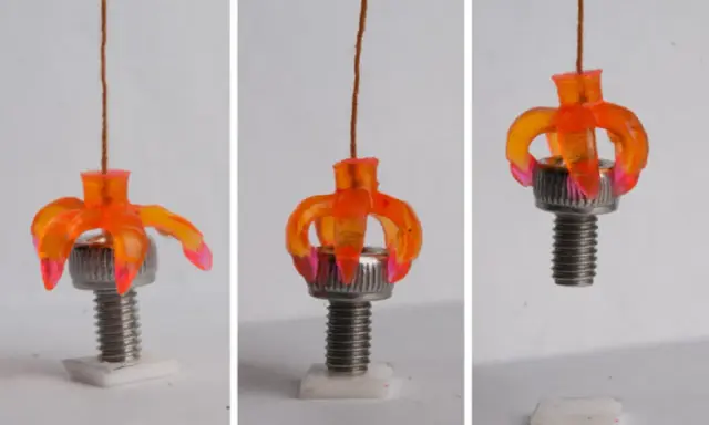 Un oggetto stampato in 4d, simile a un fiore arancione, si apre e si chiude attorno a un bullone, dimostrando la sua flessibilità.