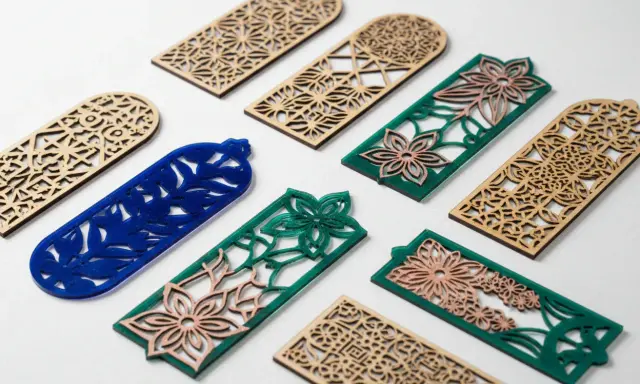Segnalibri in legno e acrilico con intricati **progetti laser** floreali e geometrici.