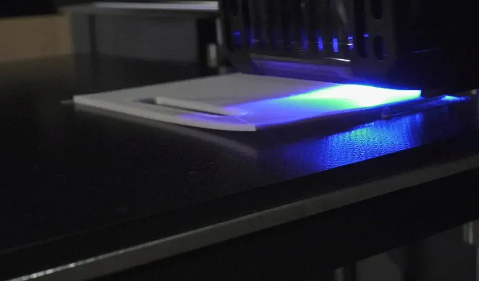 La stampa 3D in resina mostra un leggero warping, con la luce UV che illumina la superficie.