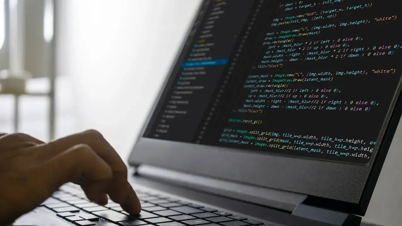 Mani che digitano su un laptop, mostrando codice per lavorare come programmatore.