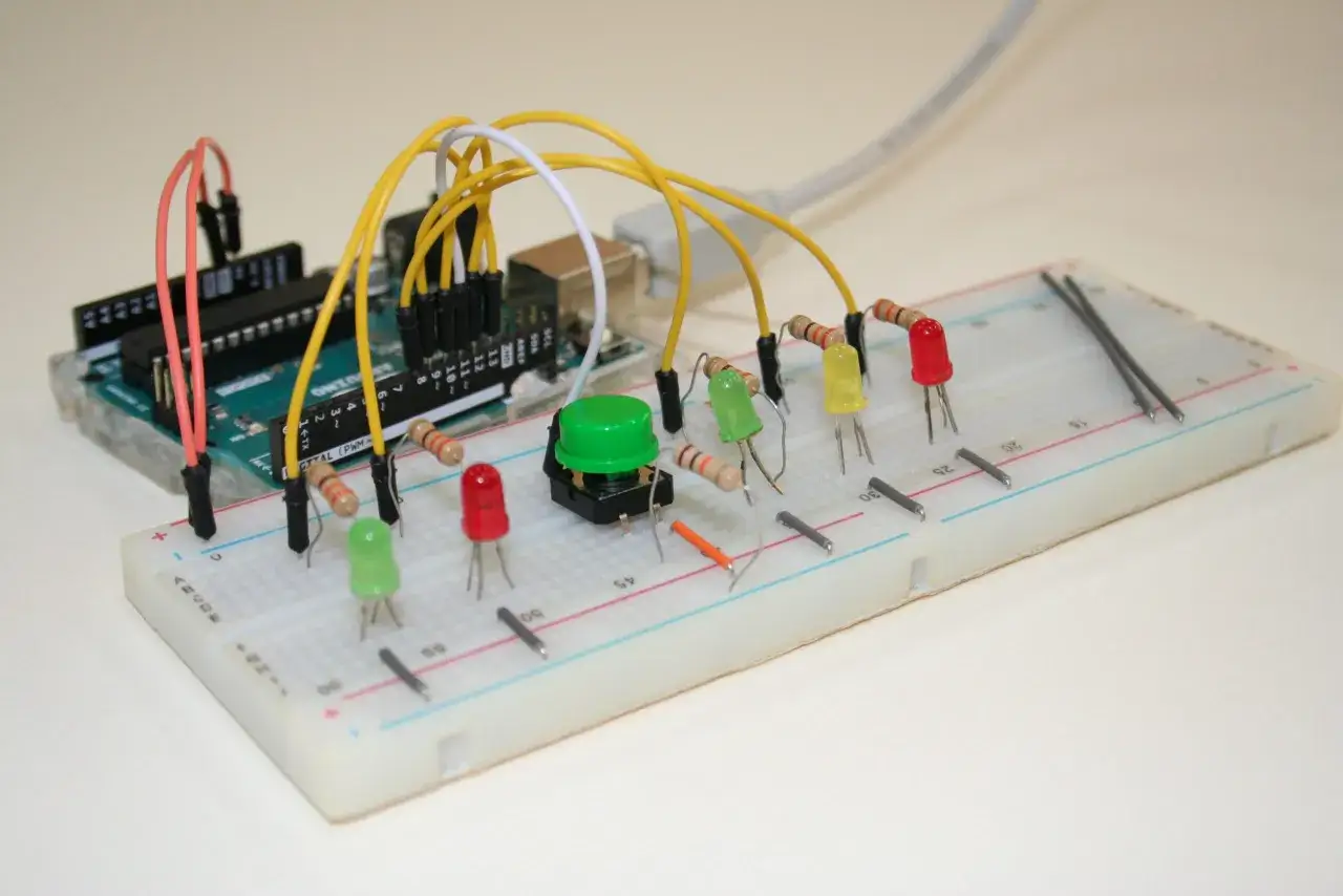 Un semaforo fai da te su breadboard con Arduino, LED rossi, gialli e verdi, e un pulsante.