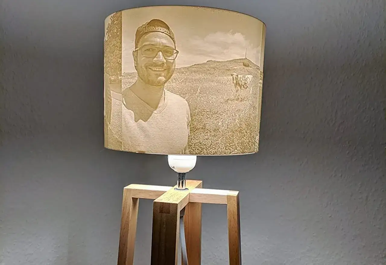 Lampada con paralume che mostra un ritratto di uomo e un paesaggio con mucca, un esempio di litofanie 3d.