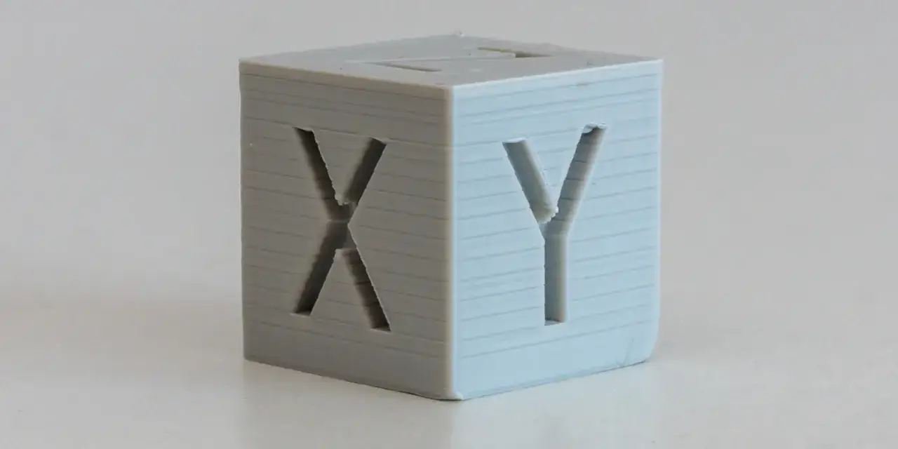 Cubo stampato in 3D con lettere X e Y incise, mostra un leggero z wobble sulle pareti.