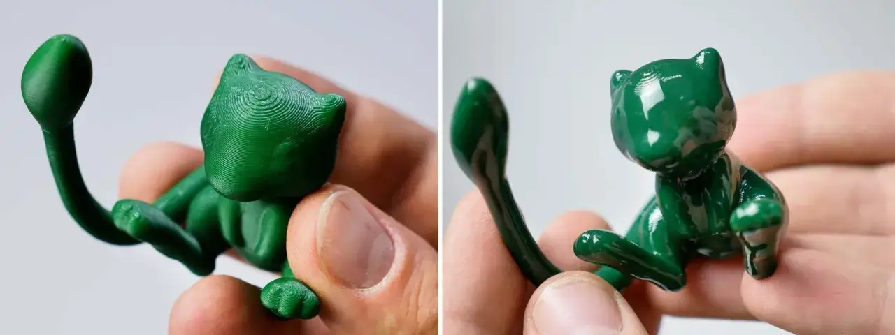 Un gattino verde lucido, stampato in 3D con pla acetone, tenuto tra le dita.