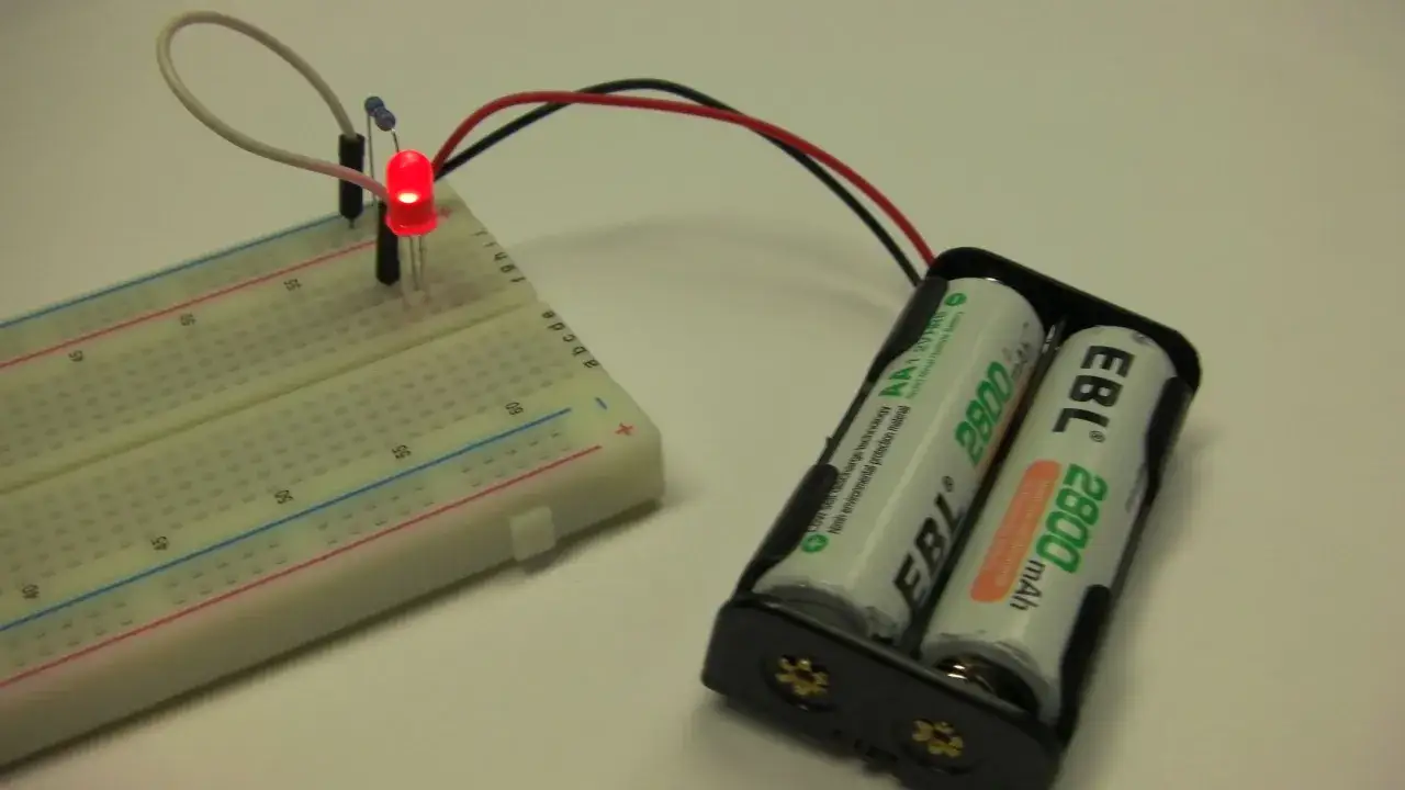 Un semplice circuito led alimentato da batterie, con un diodo rosso acceso su una breadboard.