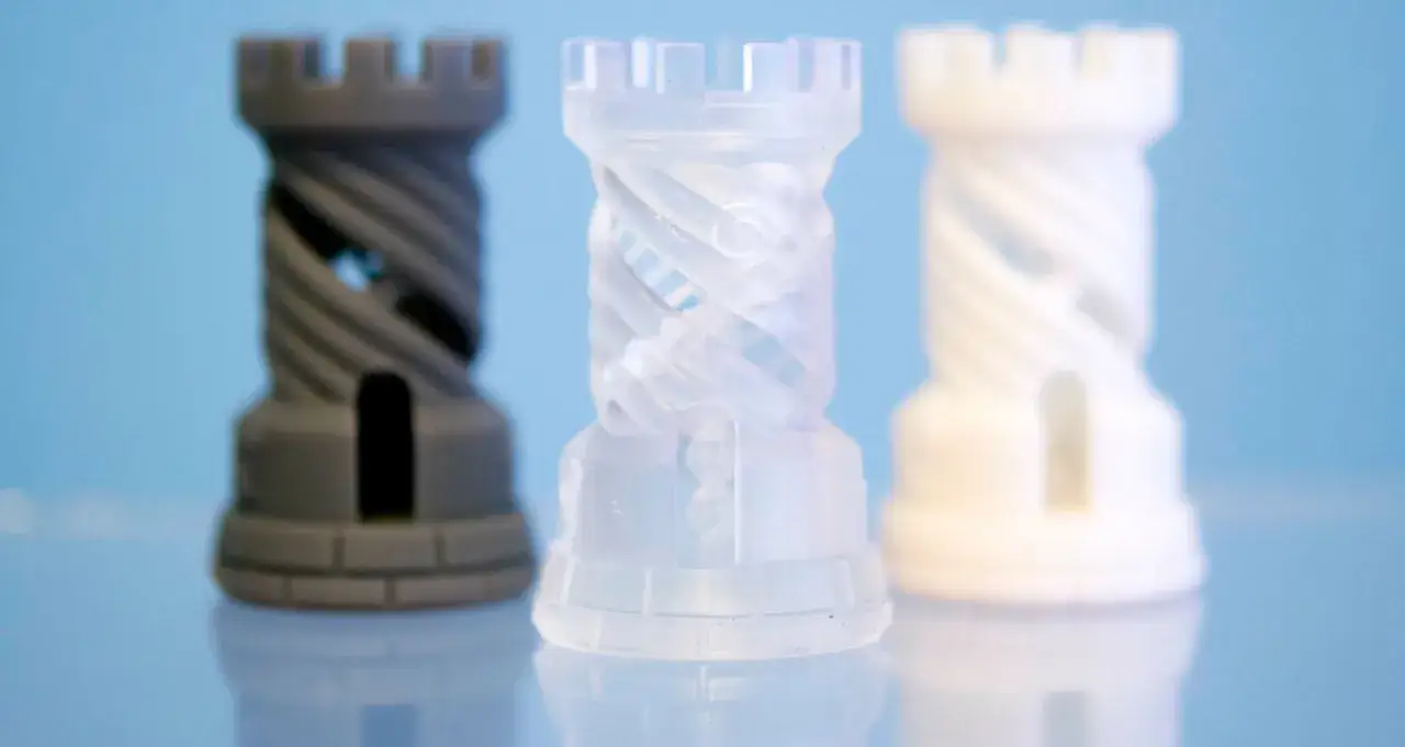 Tre torri di scacchi realizzate con stampa 3d resina, grigia, trasparente e bianca, con dettagli a spirale.