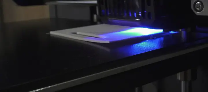 La stampa 3D in resina mostra un leggero warping, con la luce UV che illumina la superficie.